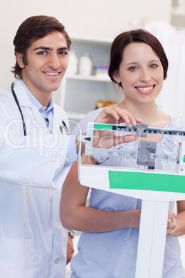 Smiling doctor adjusting scale for his patient