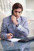 Businessman taking notes while on the phone