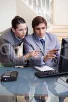 Businessman showing whats on his screen to his colleague