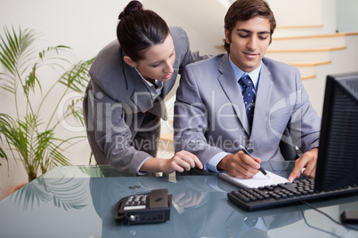 Businessman taking notes while getting mentored by colleague