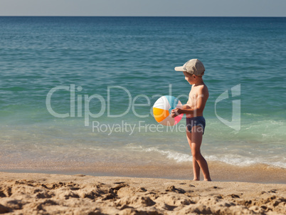 Child boy holding ball on sea sand beach