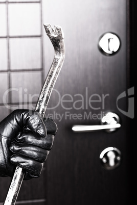 Burglar hand holding crowbar break opening door