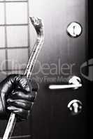 Burglar hand holding crowbar break opening door