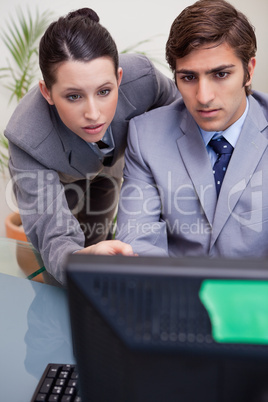Businesswoman helping her colleague with computer problems