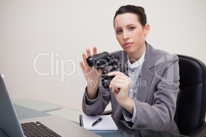 Businesswoman on her desk with binoculars