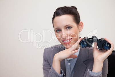 Smiling businesswoman with binoculars