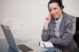 Smiling businesswoman with headset on her laptop