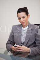 Businesswoman behind desk with cellphone