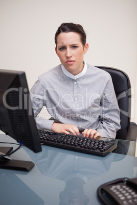 Businesswoman behind her desk looking confused
