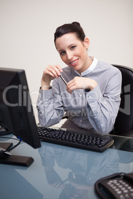 Smiling businesswoman with pen sitting at her desk