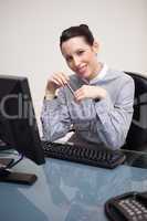 Smiling businesswoman with pen sitting at her desk