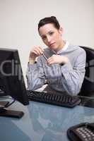 Businesswoman holding pen sitting behind a desk