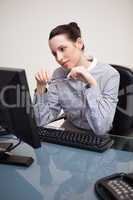 Businesswoman looking at screen holding her glasses