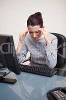 Businesswoman having a headache at her desk