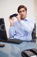 Businessman with binoculars in his office