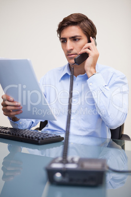 Businessman holding paperwork while on the phone