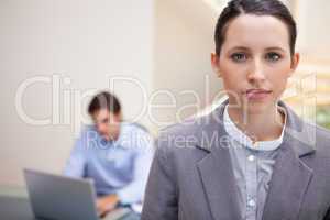 Businesswoman with colleague on his laptop behind her