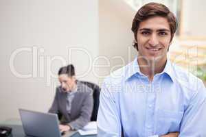 Smiling businessman with colleague on her laptop behind him