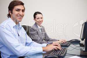 Side view of smiling colleagues working next to each other