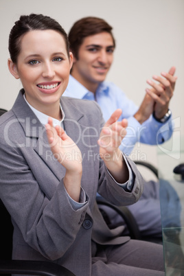 Side view of clapping business team sitting at desk