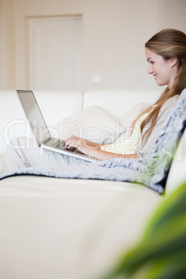 Side view of woman with her laptop sitting on the sofa