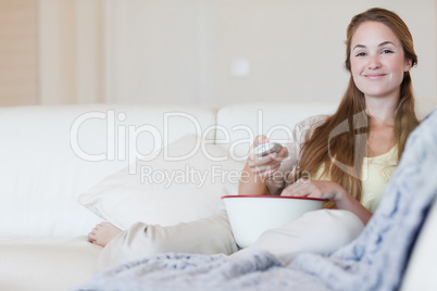 Smiling woman enjoying a movie with a bowl of popcorn