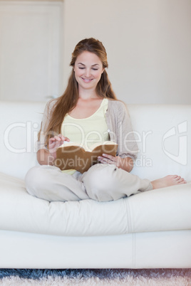 Woman enjoys reading a book on her sofa