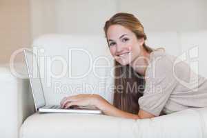 Side view of woman lying on the sofa surfing the internet