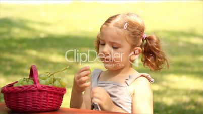 little girl eat grape