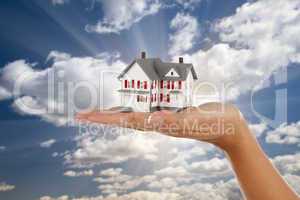 Model House in Female Hand on Sky Background