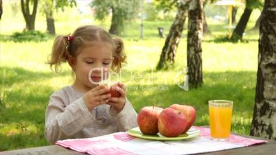 little girl eat apple in park