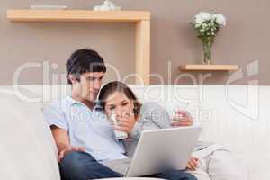 Happy couple with their laptop on the sofa