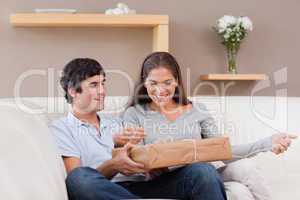 Couple opening parcel on the sofa