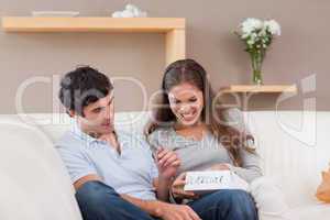 Woman opening present from her boyfriend on the sofa