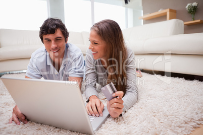 Couple lying on the floor shopping online