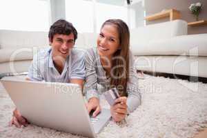 Couple lying on the floor booking holidays online
