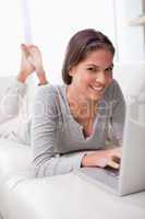 Smiling woman lying with notebook on the sofa