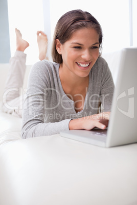 Smiling woman chatting online on her sofa