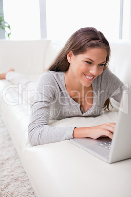 Woman on the sofa typing on her notebook