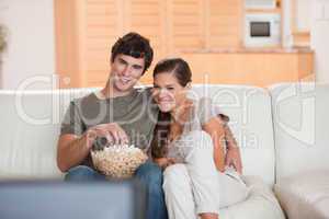 Couple with popcorn on the sofa watching a movie