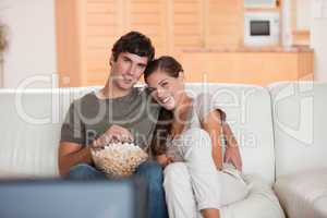 Couple with bowl of popcorn watching a movie on the sofa