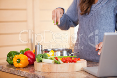 Woman adding herbs to her vegetable stew