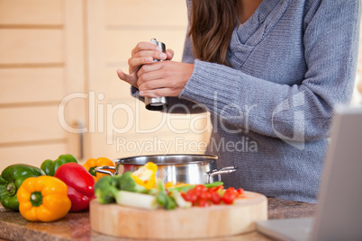 Woman adding pepper to her vegetable stew