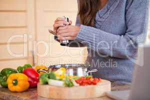 Woman adding pepper to her vegetable stew