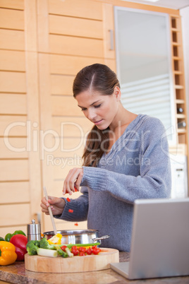 Woman adding carrot pieces to her stew