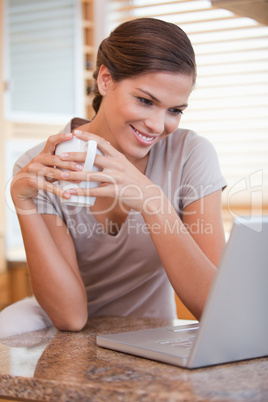 Woman with coffee and laptop in the kitchen