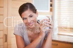 Smiling woman holding a cup in the kitchen