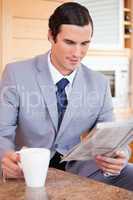 Businessman in the kitchen reading news and having coffee