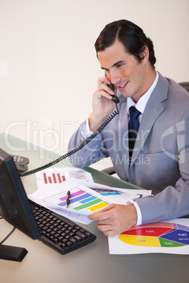 Smiling businessman talking about statistics on the phone