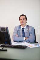 Businessman with arms folded waiting for his computer